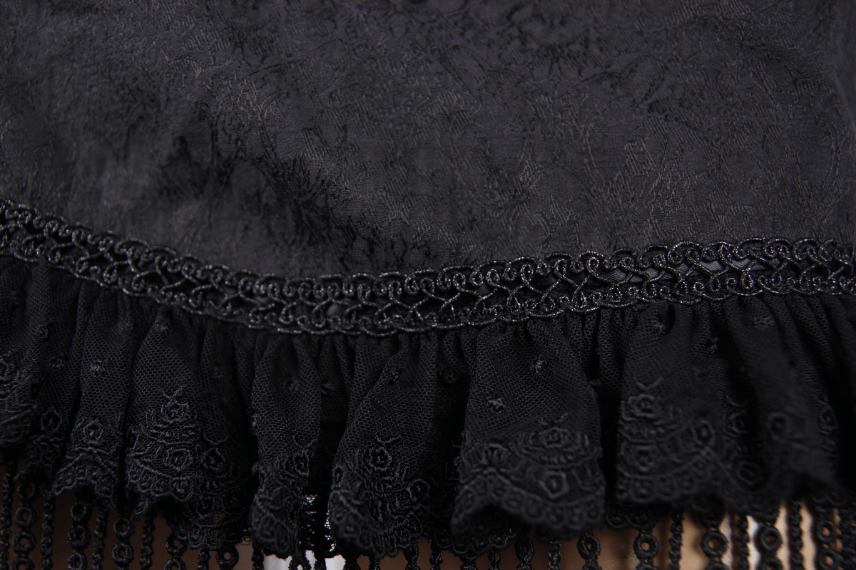 Close-up of black lace tassels and ruffled fabric on a gothic short skirt, showcasing elegant design details.