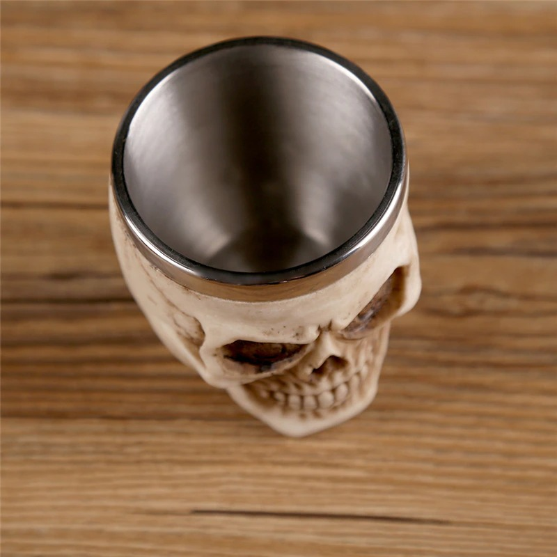 Gothic stainless steel skull shot glass showcasing intricate design details on a wooden surface.