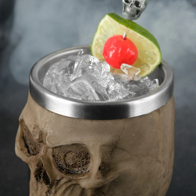 Gothic stainless steel skull cup filled with ice, garnished with lime and cherry for a spooky drink experience.