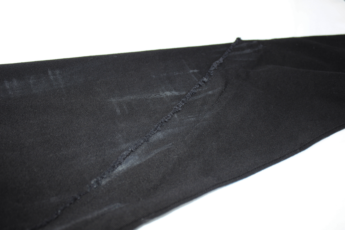 Close-up of Gothic slim fit black pants featuring lace-up detail on the right leg and stylish textured fabric.