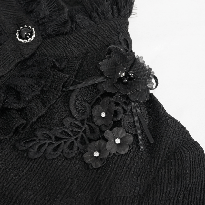 Close-up of black appliquéd flowers on gothic blouse with ruffles and buttons, showcasing stylish details.