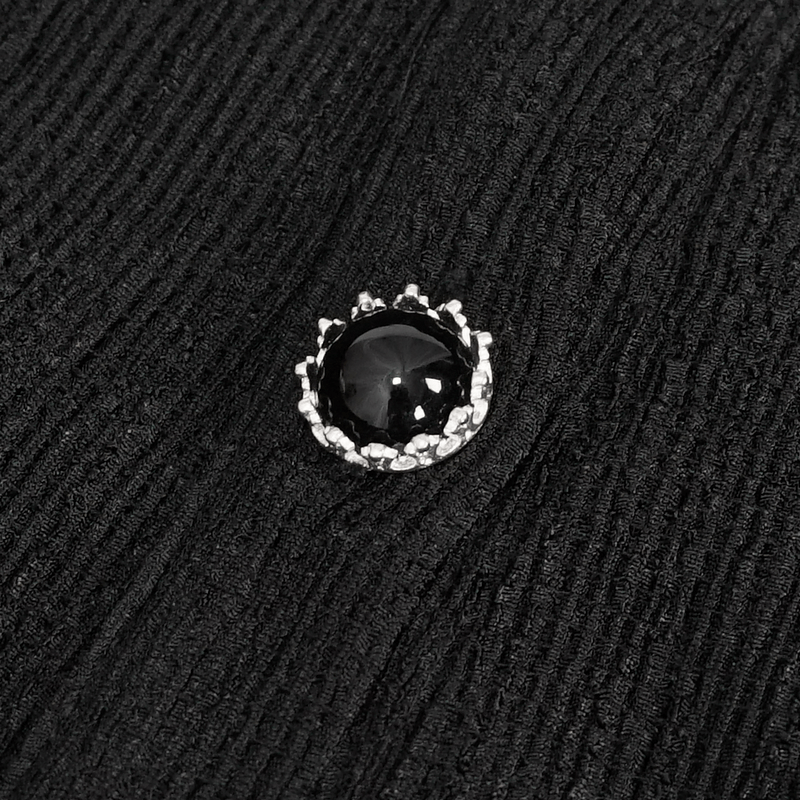 Close-up of a stylish black button with a sparkling design on gothic fabric.