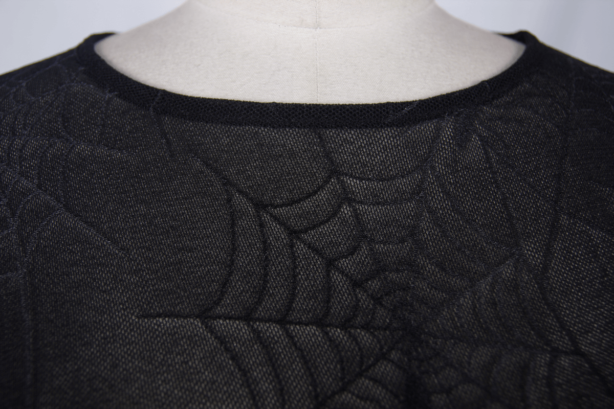 Close-up of a black women's top featuring a spider web pattern, showcasing its gothic and trendy style.