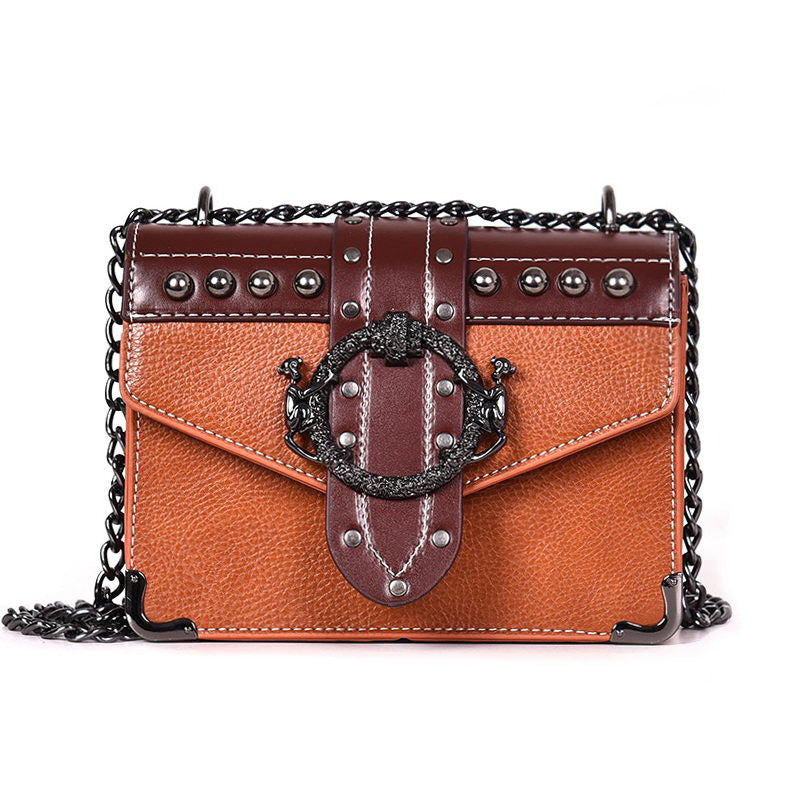 Gothic-style female small square bag with rivet lock, chain strap, and skull details in brown and orange.