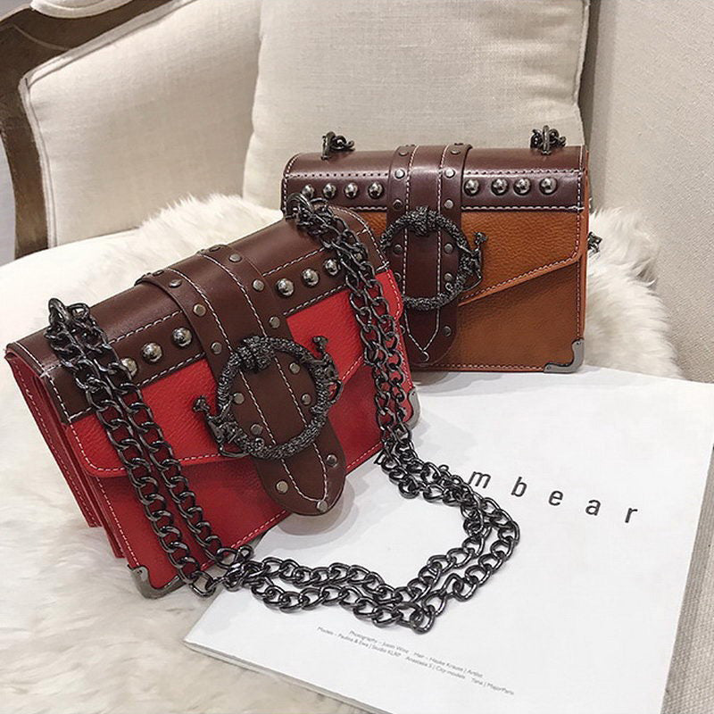 Gothic style small bags with chain strap in red and brown, featuring metal rivets and locks, placed on a soft surface.