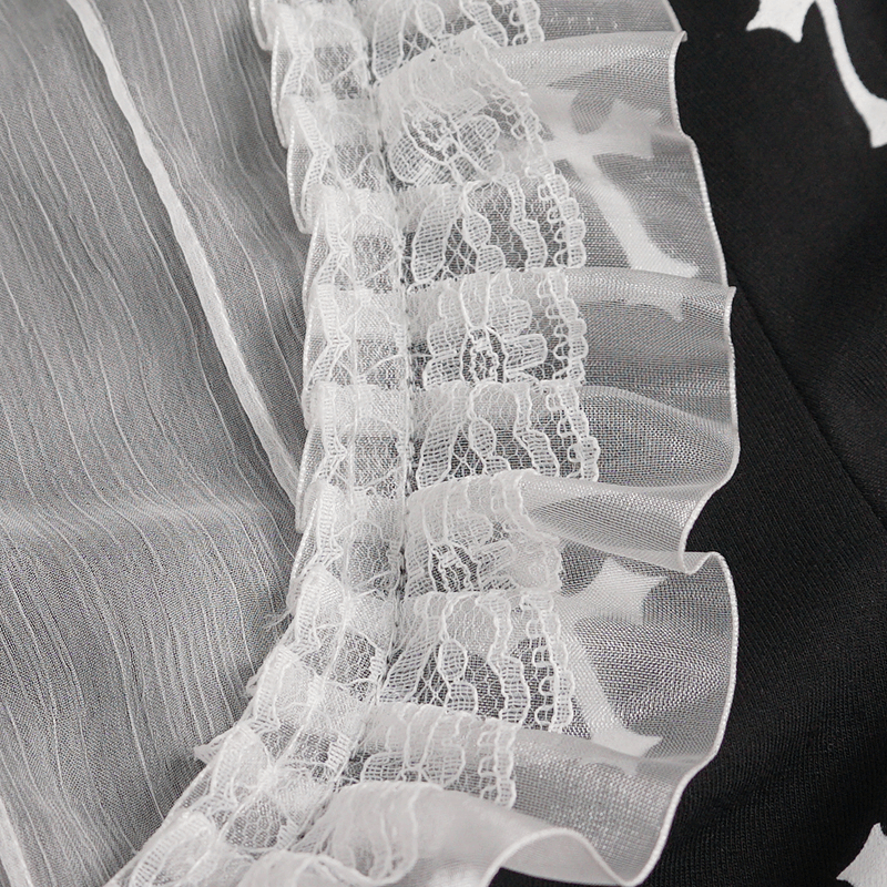 Close-up of ruffled lace detail on Gothic style blouse with white crosses pattern, showcasing alternative women's fashion.