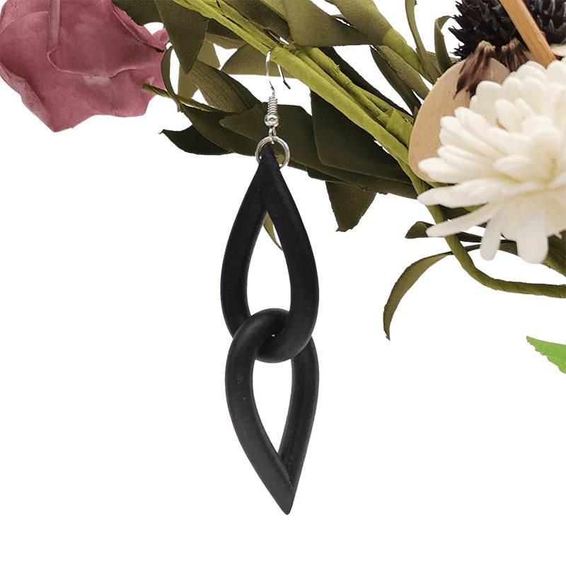 Handmade gothic black rubber earrings hanging among flowers, perfect for stylish women's accessories.