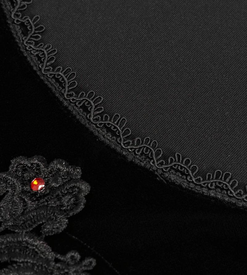 Close-up of black velvet top with intricate lace trim and floral appliqué detail, featuring a sparkling jewel.