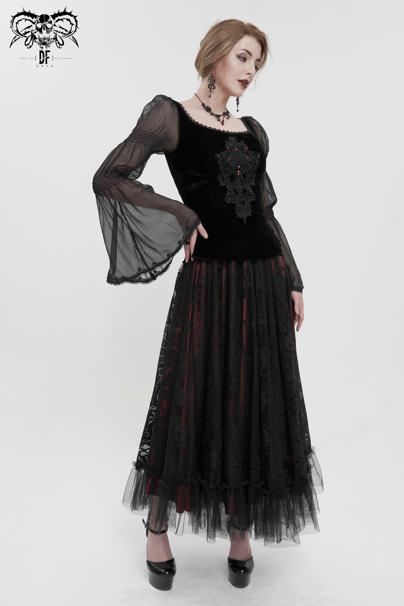 Elegant woman in gothic velvet top with transparent long sleeves and lace detailing, wearing a flowing black skirt.