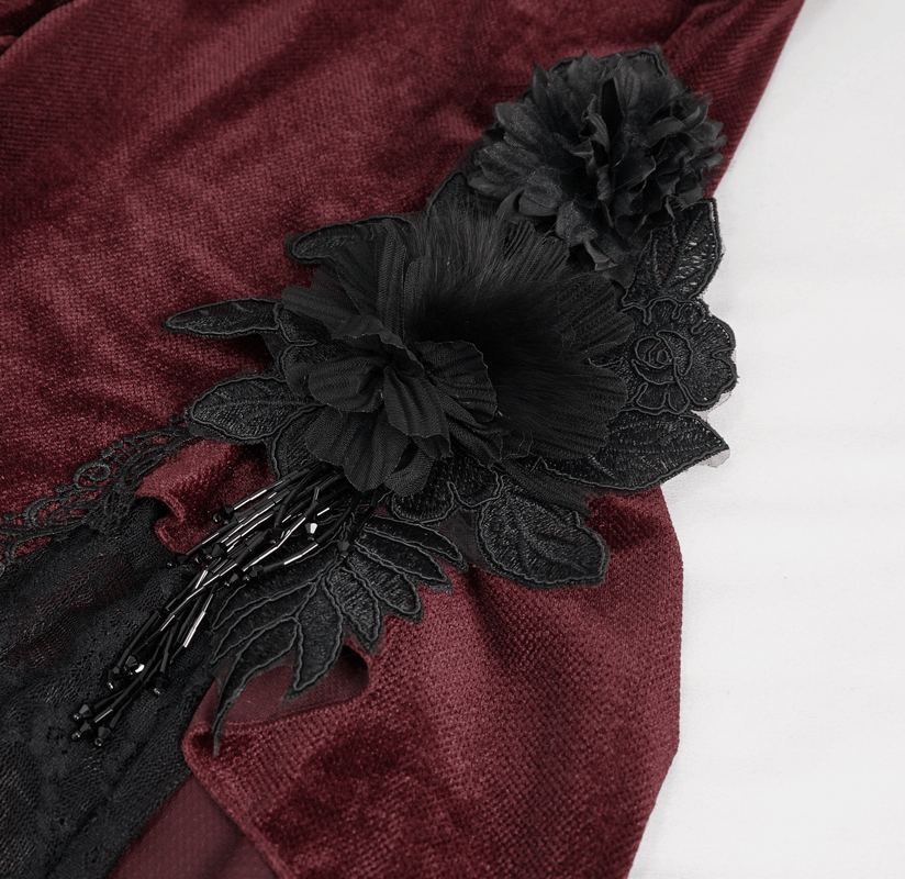Close-up of gothic lace detail and black flower accents on wine red flared pants for a trendy look.