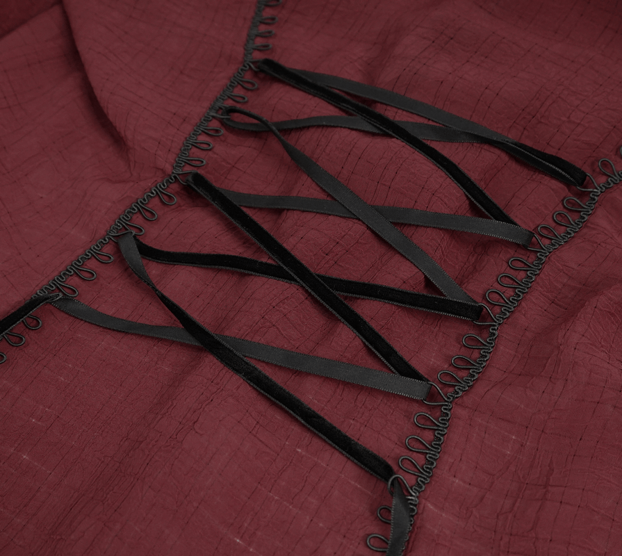 Close-up of wine red fabric with black lace-up details and ribbons, showcasing gothic style elegance.