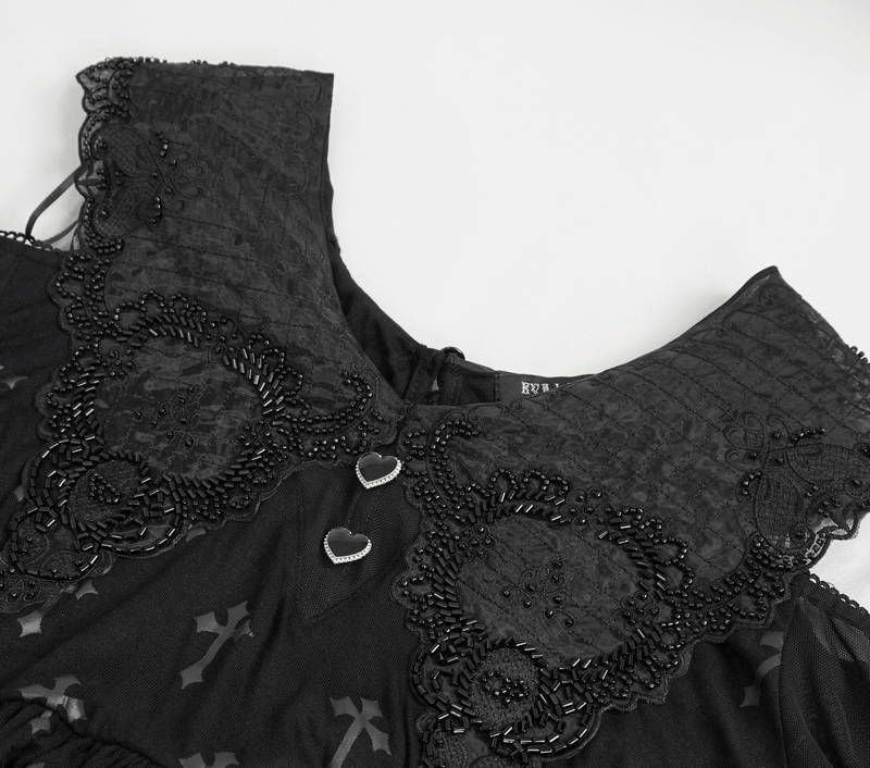Close-up of gothic women's off-shoulder dress with embroidered details and heart-shaped buttons.