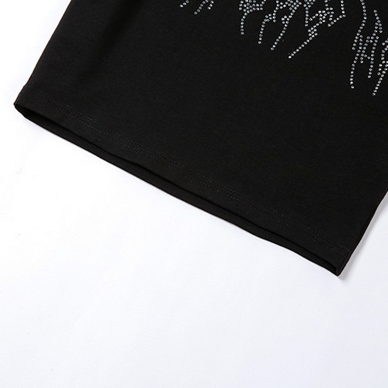 Close-up of the hem of a gothic women's black crop top with sequin spider design.