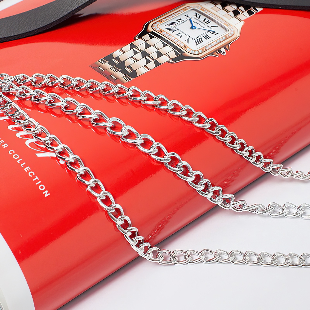 Gothic women's faux leather belt with metal chains laid over a magazine, showcasing punk style and edgy fashion.