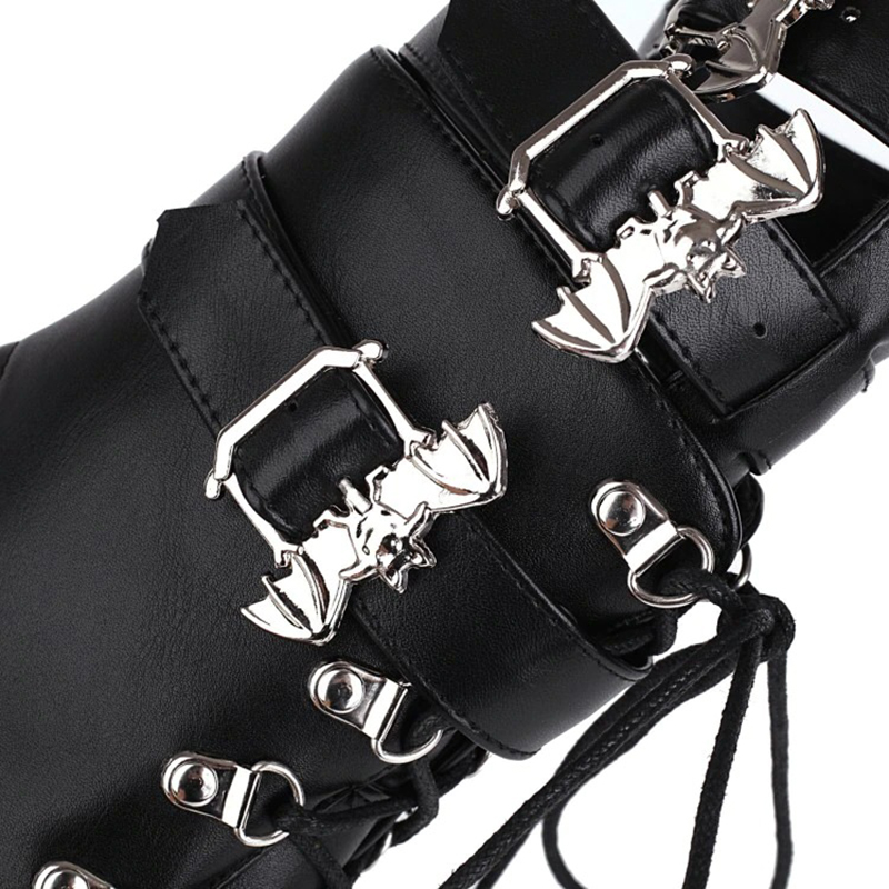 Close-up of gothic women's patent leather boots featuring stylish bat buckles and lace detail.