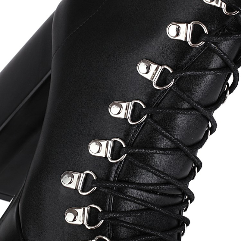 Close-up of gothic black high heel boots with stylish lacing and metallic buckles for a chic look.