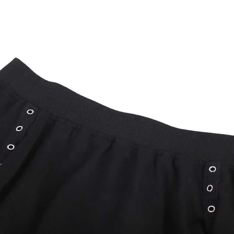 Close-up of a black women's crop top featuring circular silver rivets for a gothic streetwear look.