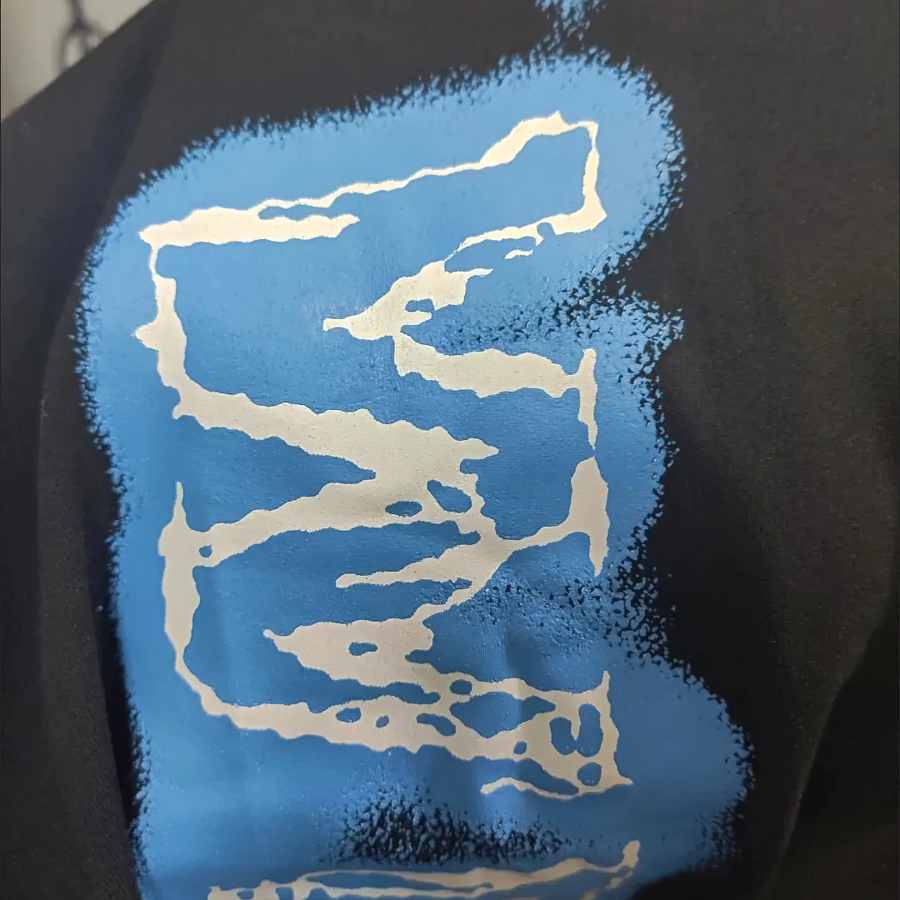 Close-up of a black fabric featuring a vibrant blue and white abstract print design.