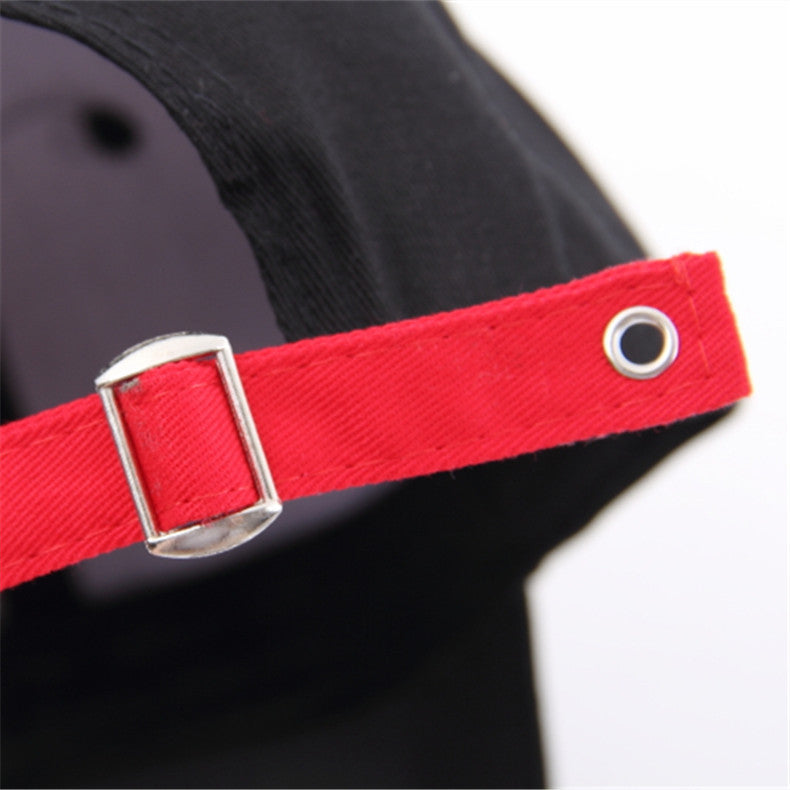 Close-up of red adjustable strap on a black snapback baseball cap, showing buckle and eyelet details.
