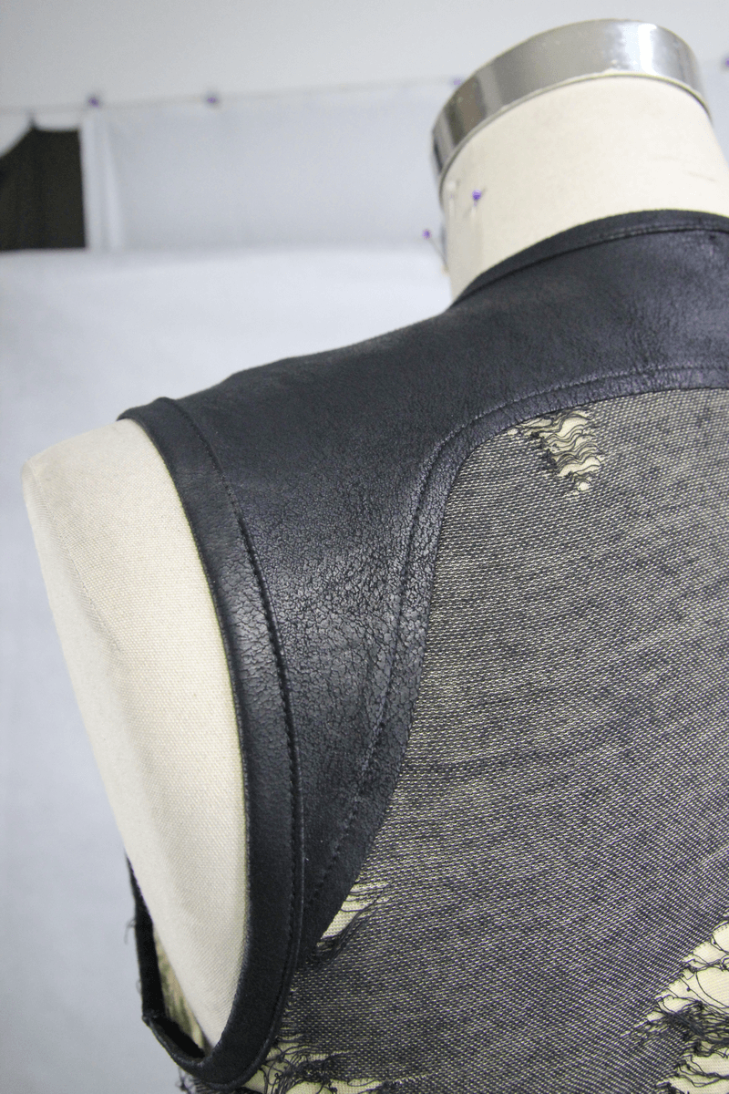 Close-up of the back of a men's grunge tank top featuring a leather-like shoulder and distressed mesh fabric.