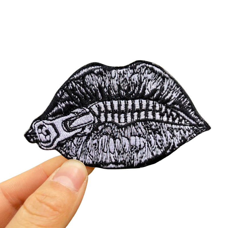 Grunge style zipped lips patch held in hand, perfect goth accessory for men and women.