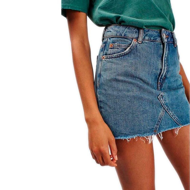 Model wearing a grunge style high waist A-line mini skirt in denim blue, featuring pockets and a casual green shirt.