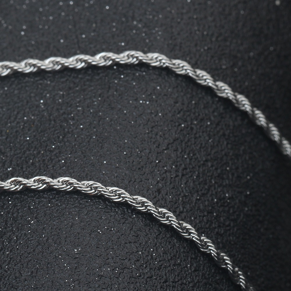 Close-up of twisted stainless steel chain necklace on black background, stylish accessory for rock enthusiasts.