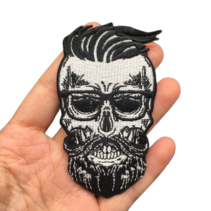 Hand holding a hairy skull patch with beard and mustache, perfect for gothic clothing accessories.