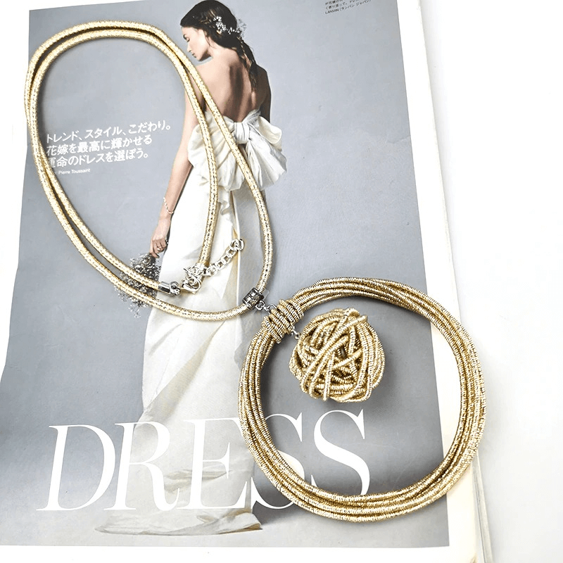 Stylish handmade gold metal necklace with round pendant on a fashion magazine featuring wedding dress.