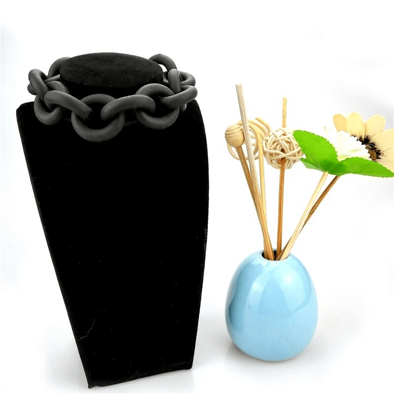 Handmade black rubber bangle displayed on a black bust, paired with a blue vase and decorative sticks.