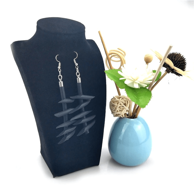 Handmade rubber long earrings for women styled on a black display bust next to a blue vase with flowers.