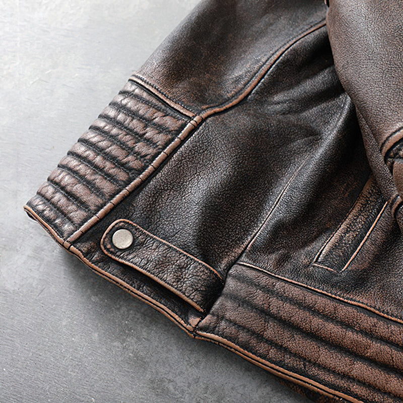 Close-up of vintage brown leather motorcycle jacket sleeve showcasing ribbed detailing and snap button.