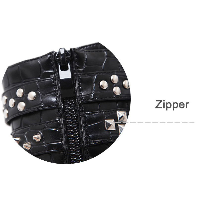 Close-up of zipper detail on black patent leather ankle boots with chains and studs, showcasing Gothic style.