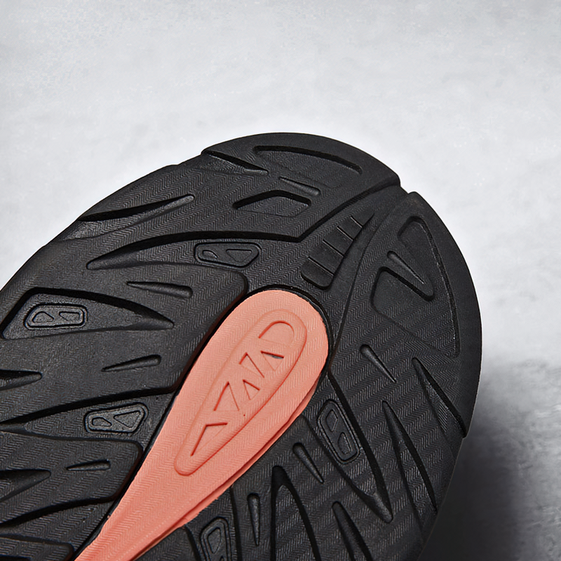 Close-up of a rubber outsole featuring a unique tread pattern and a vibrant orange accent.