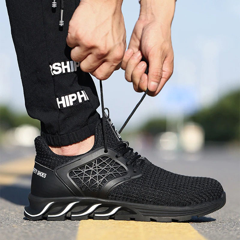 Close-up of a man tying the laces of stylish black breathable sneakers for safety and comfort.