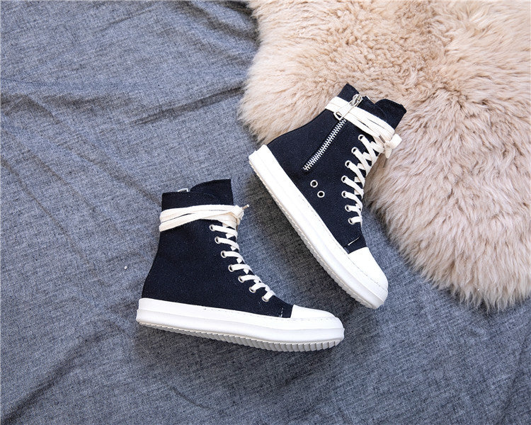 Stylish black high top retro platform sneakers with white laces on a soft gray background.