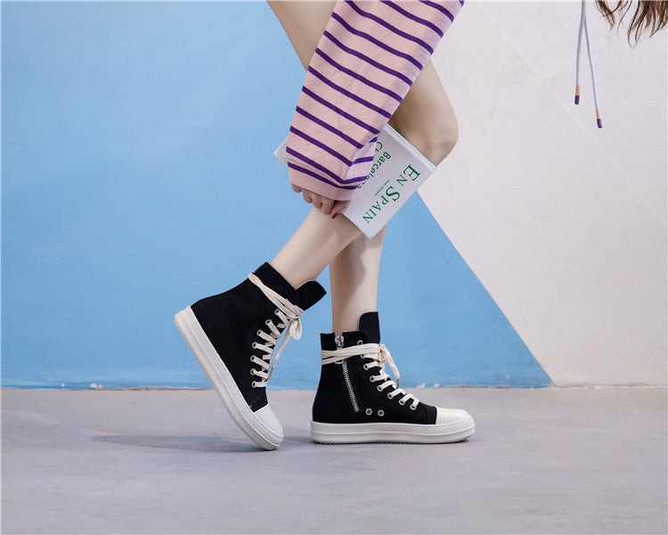 Female model wearing retro high top black sneakers with white soles, showcasing alternative fashion style.