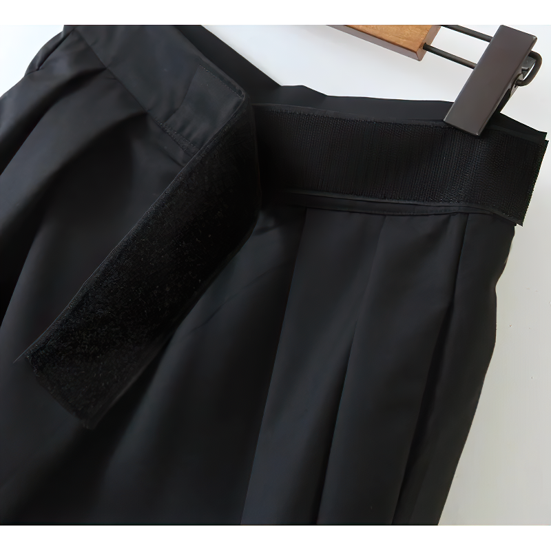 Close-up of high waist black pleated trousers waistband with velcro detail for women's fashion.