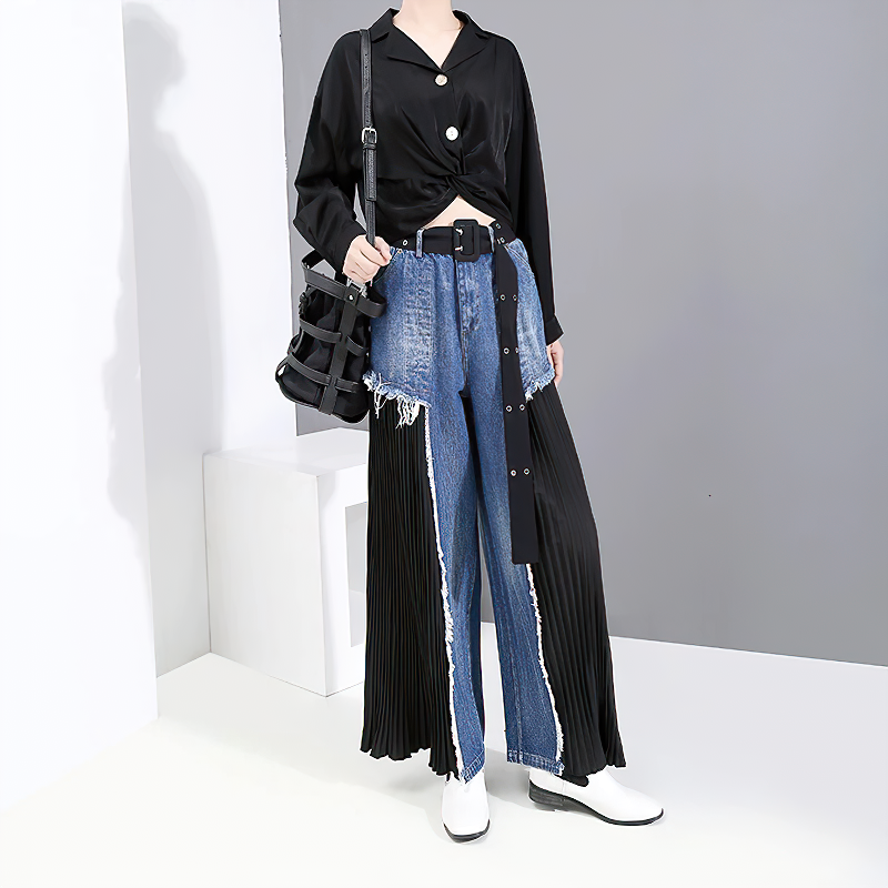 Fashionable woman in black top and unique blue denim wide pants with pleats, showcasing a trendy alternative style.