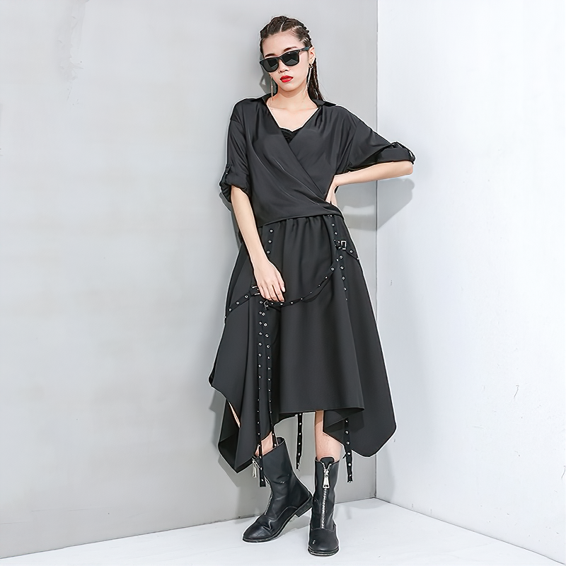Stylish woman in a black asymmetrical skirt and chic sunglasses, showcasing alternative fashion with metal rivets.
