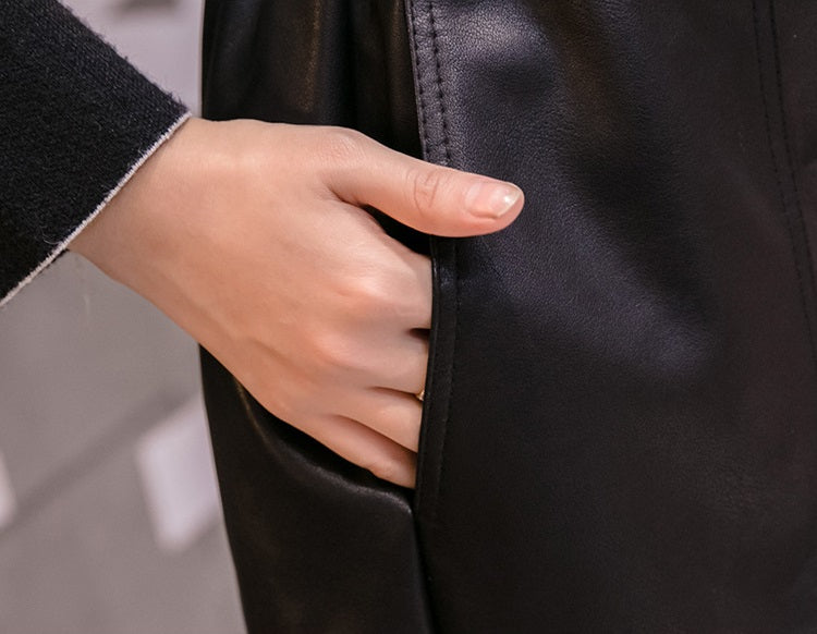 Close-up of a hand reaching into the pocket of women's high-waist faux leather shorts, showcasing its stylish design.
