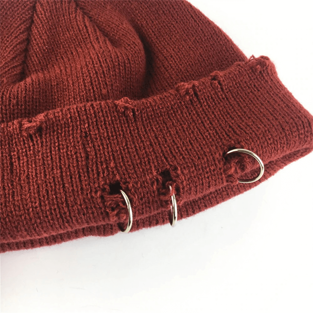 Close-up of a rust-colored knitted hat featuring stylish rings and a cozy curled design, perfect for casual outfits.