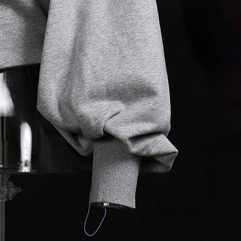 Close-up of the sleeve of a grey hollow out hooded top, showcasing its stylish puffed design for alternative streetwear.