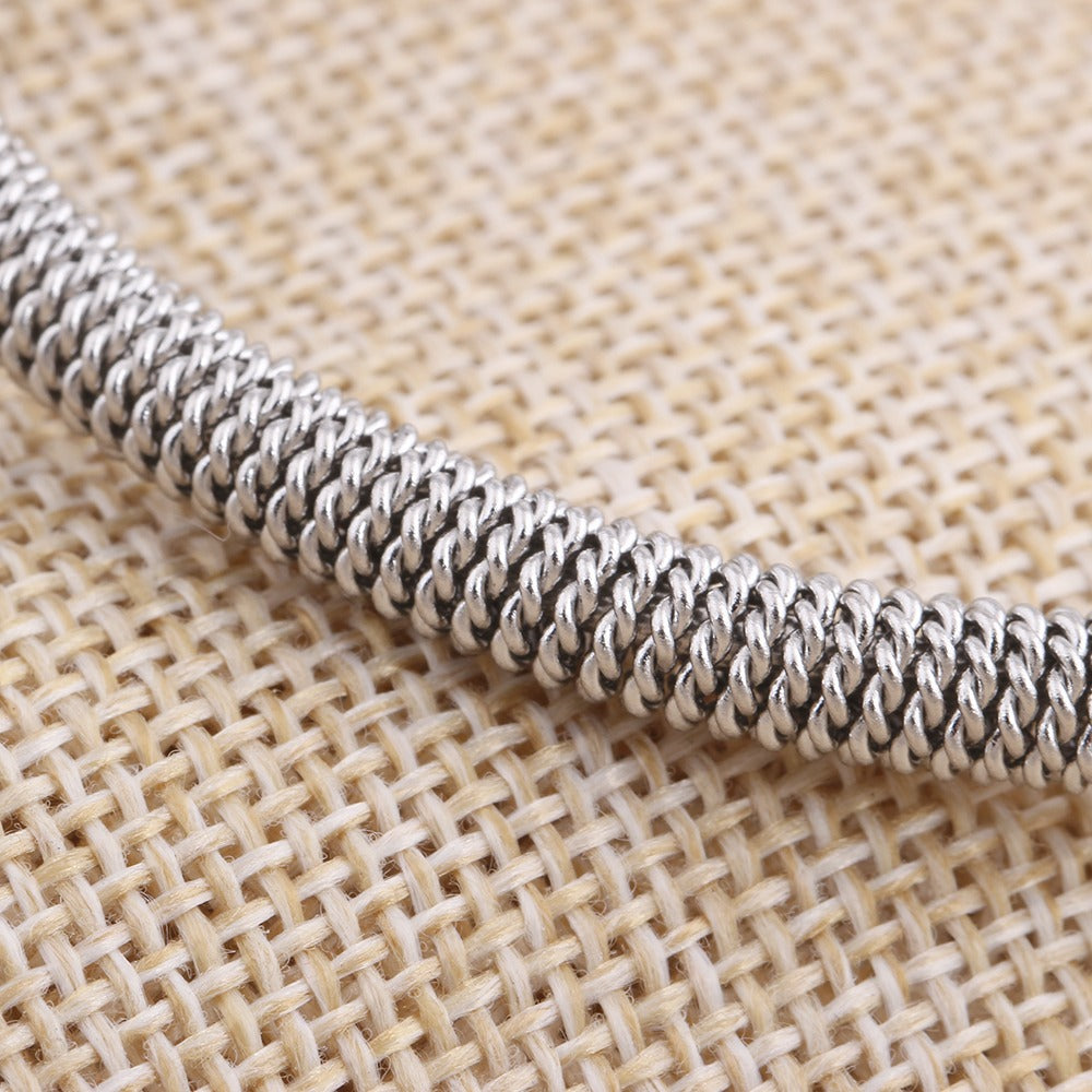 Close-up of a luxury stainless steel bracelet showcasing intricate weave design on a textured background.