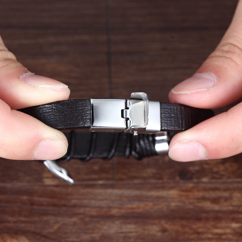 Close-up of a man's leather bracelet with stainless steel buckle showcasing vintage style and infinity logo design.