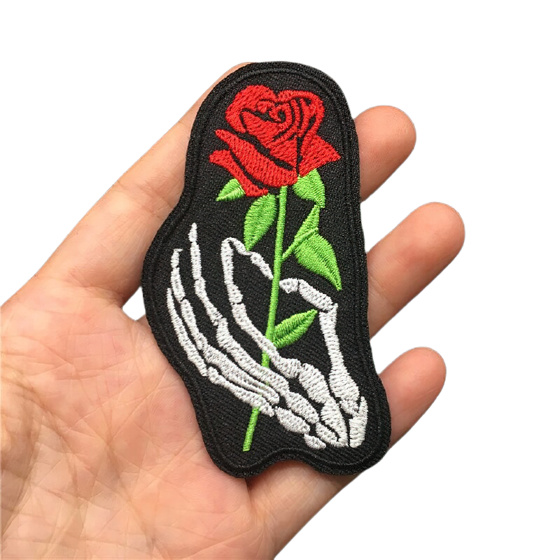 Gothic iron-on patch of a skeleton hand holding a red rose, perfect for styling clothing with a unique twist.