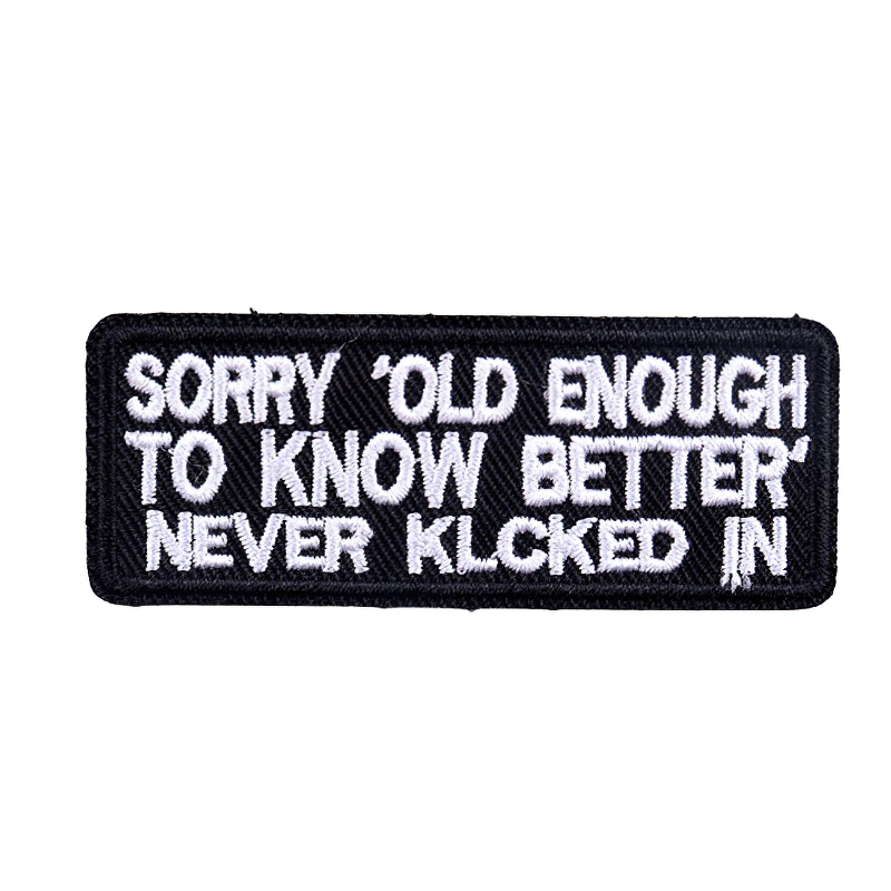 Iron-on patch with white text saying 'Sorry, OLD ENOUGH TO KNOW BETTER NEVER KLCKED IN' on a black background.
