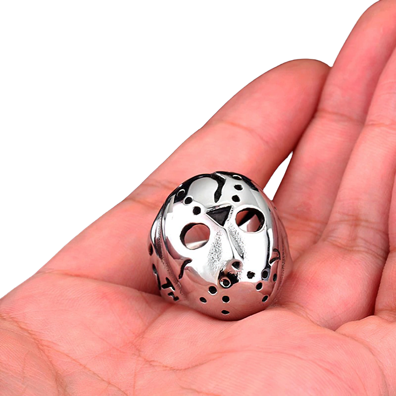Close-up of a unisex stainless steel Jason mask ring held in a hand, showcasing alternative fashion jewelry.