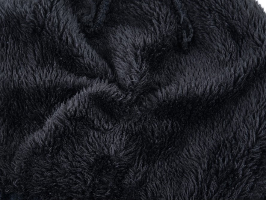 Textured black fabric close-up of a warm, fluffy winter hat, perfect for staying cozy in cold weather.