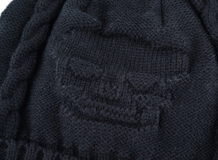 Close-up of knitted black wool beanie featuring a bold skull pattern, perfect for alternative winter fashion.